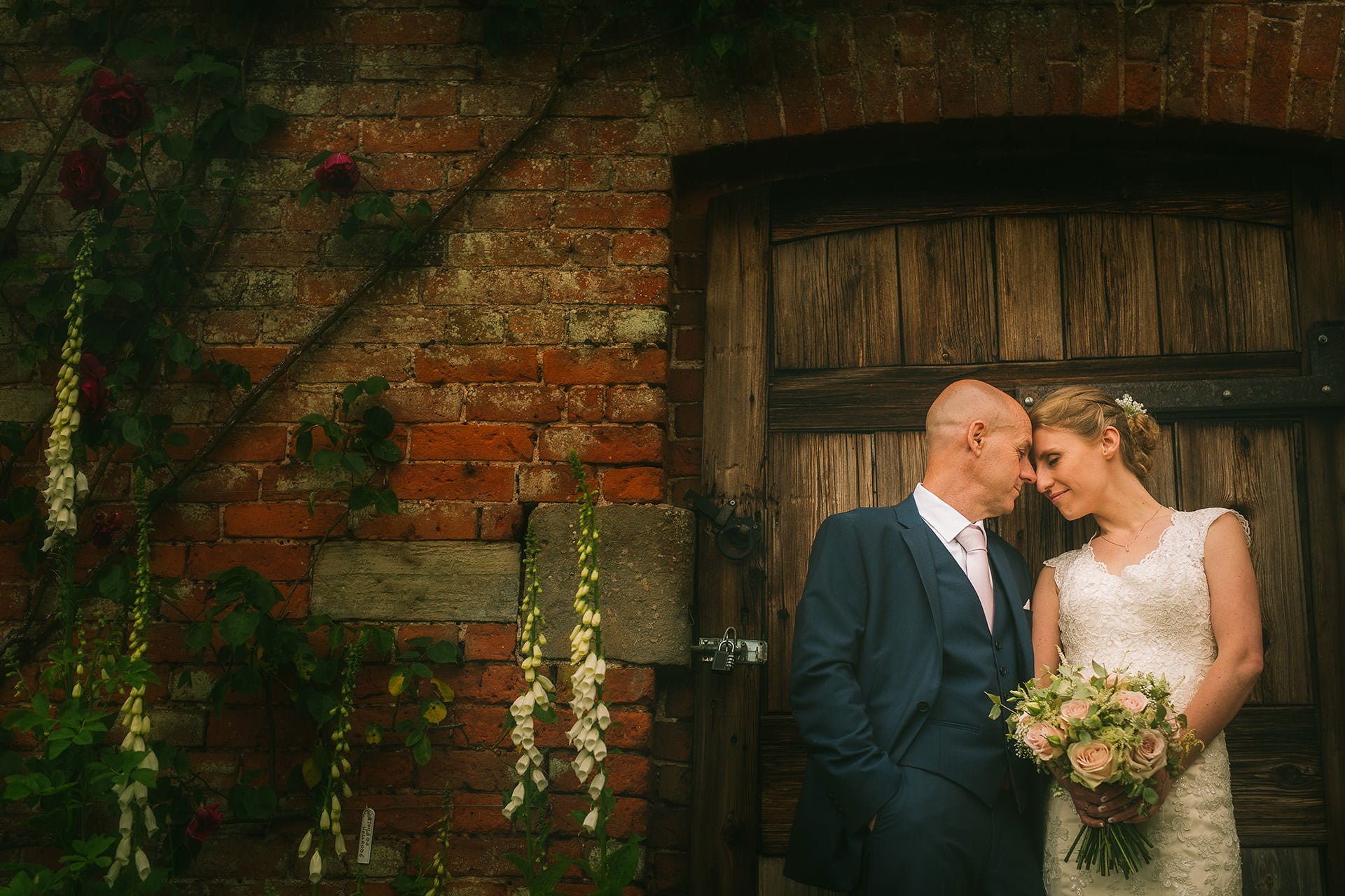 A bride and groom captured beautifully in front of a wooden door by the talented Combermere Abbey Wedding Photographer.