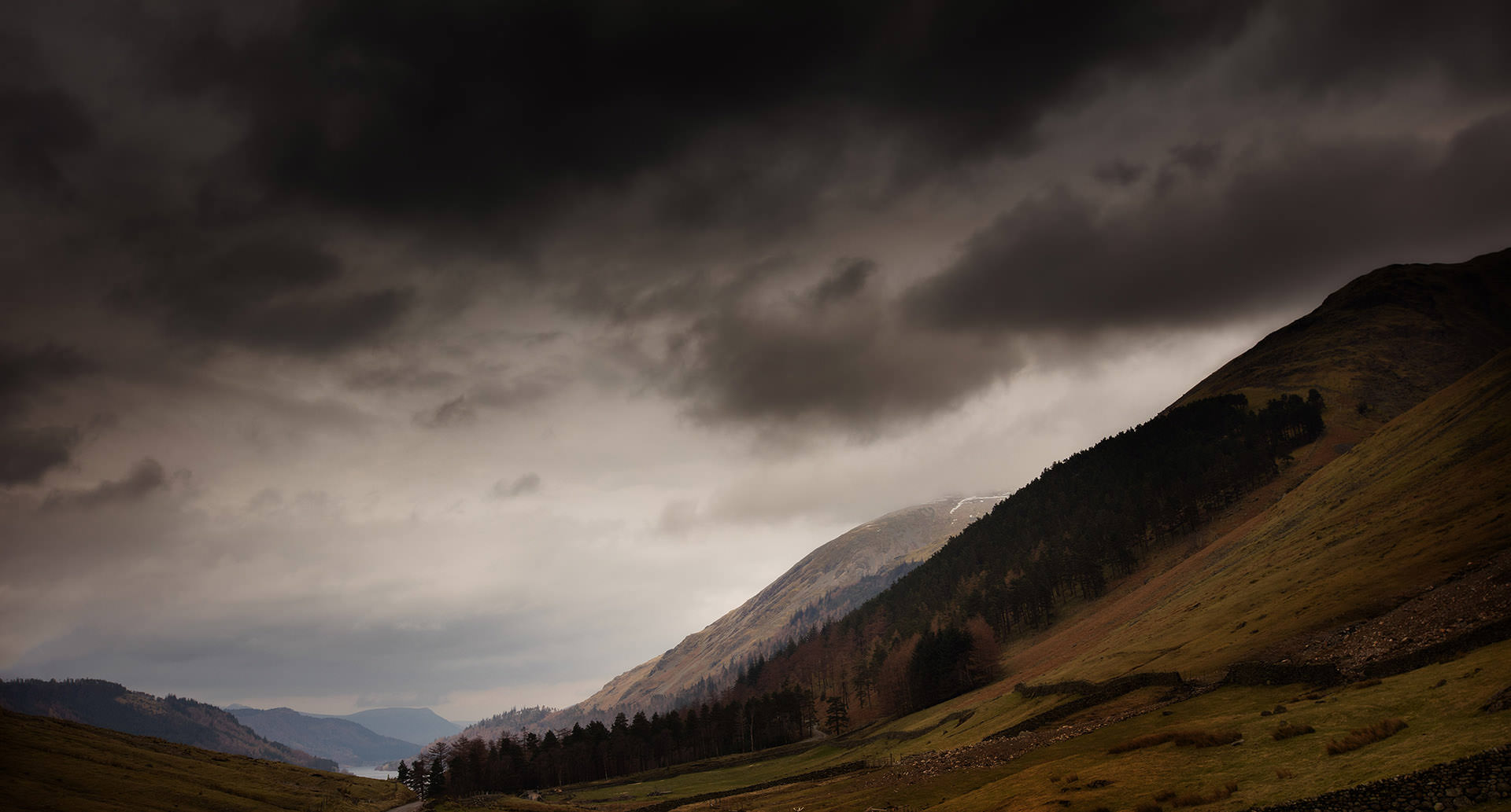 A stormy sky over a valley with mountains in the background.