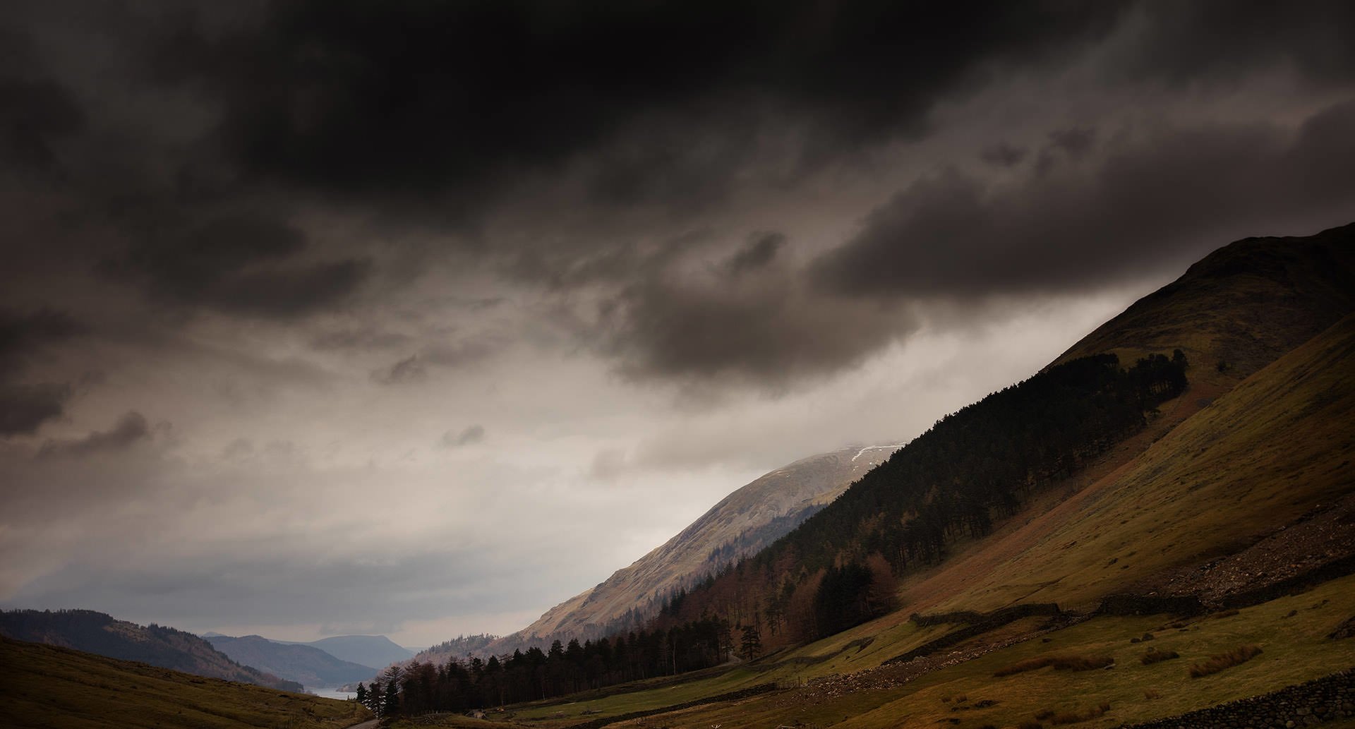 A breathtaking landscape featuring a magnificent dark sky draped over a picturesque valley, with majestic mountains towering gracefully in the background.