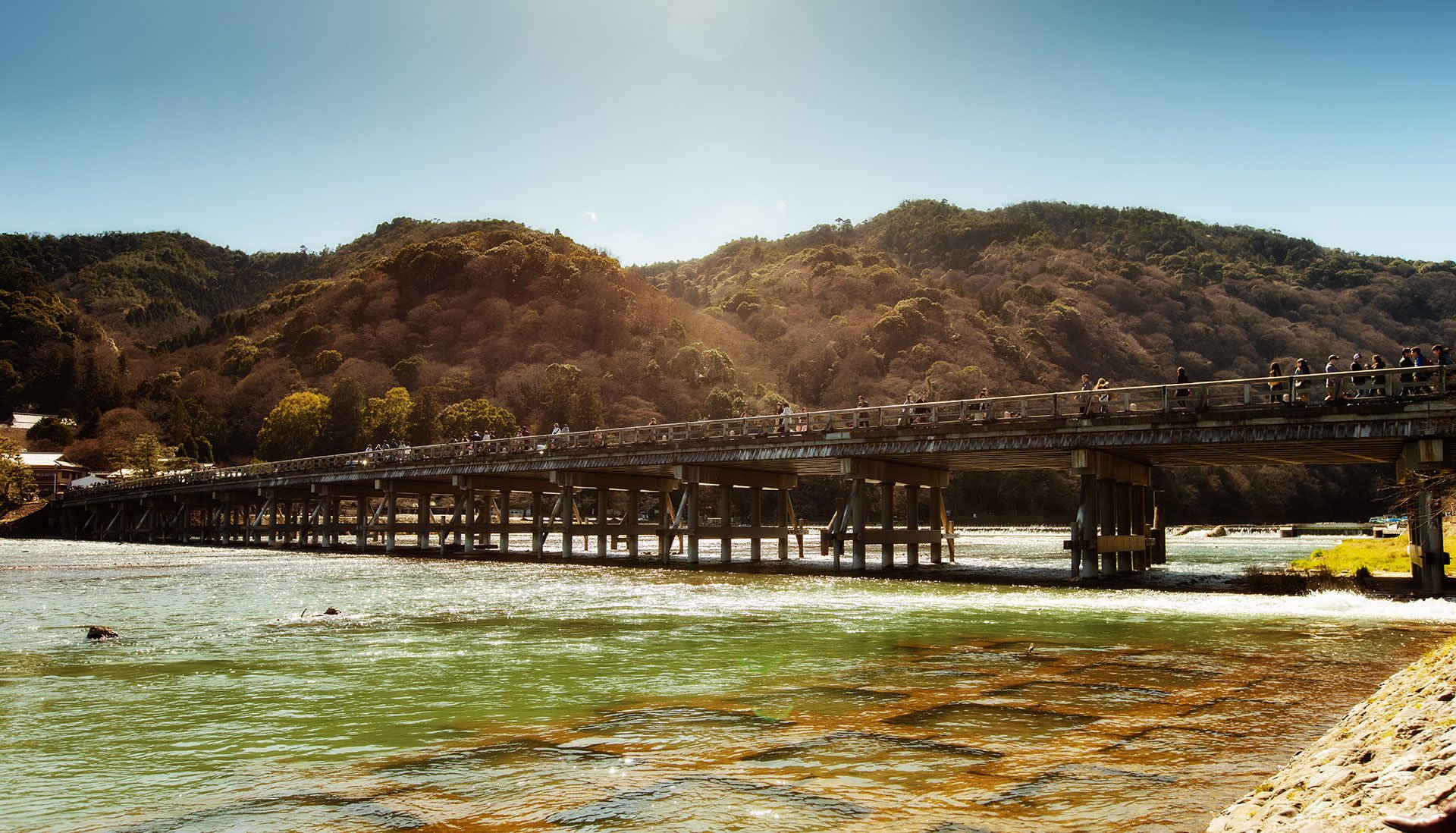 A Japanese bridge over a river with mountains in the background.