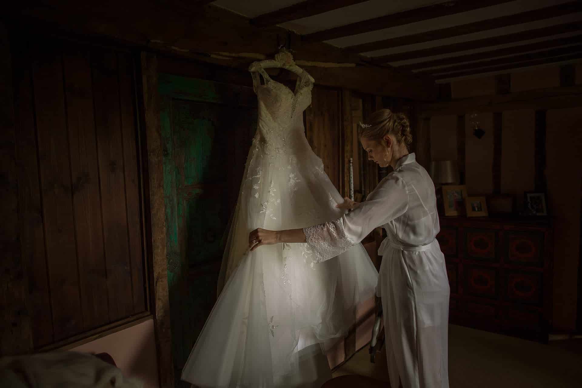Shropshire Documentary Wedding Photographer pbartworks captures Sarah tending to her dress before leaving for Delbury Hall