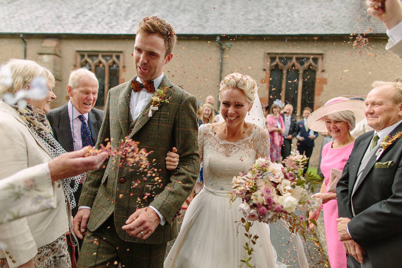 In this North Wales wedding, a bride and groom joyfully walk down the aisle showered with confetti.