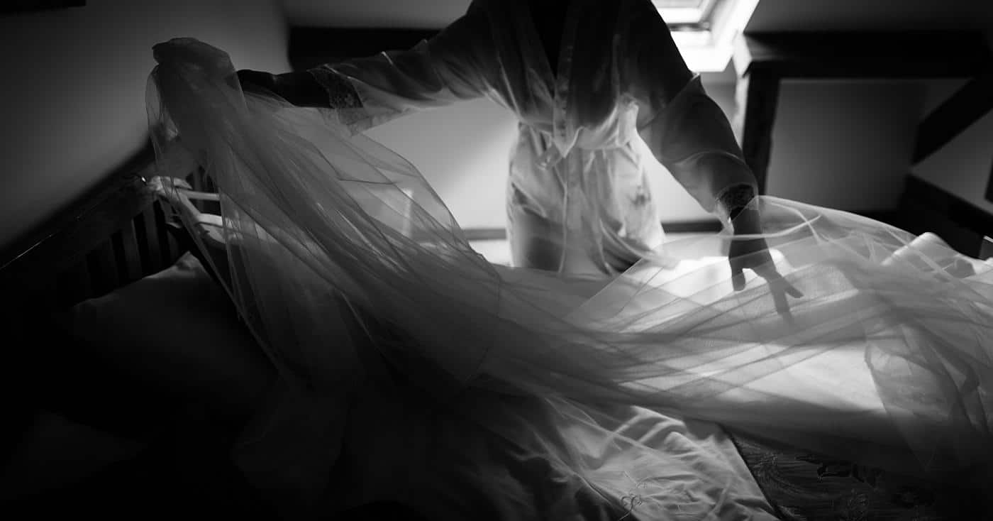 a candid moment as a bride lays out her veil and wedding dress