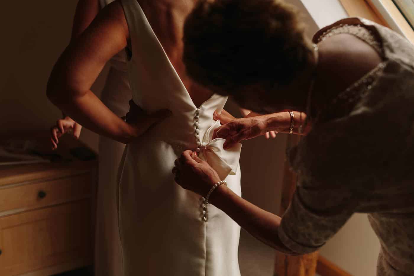 a beautiful bride is fastened into her dress