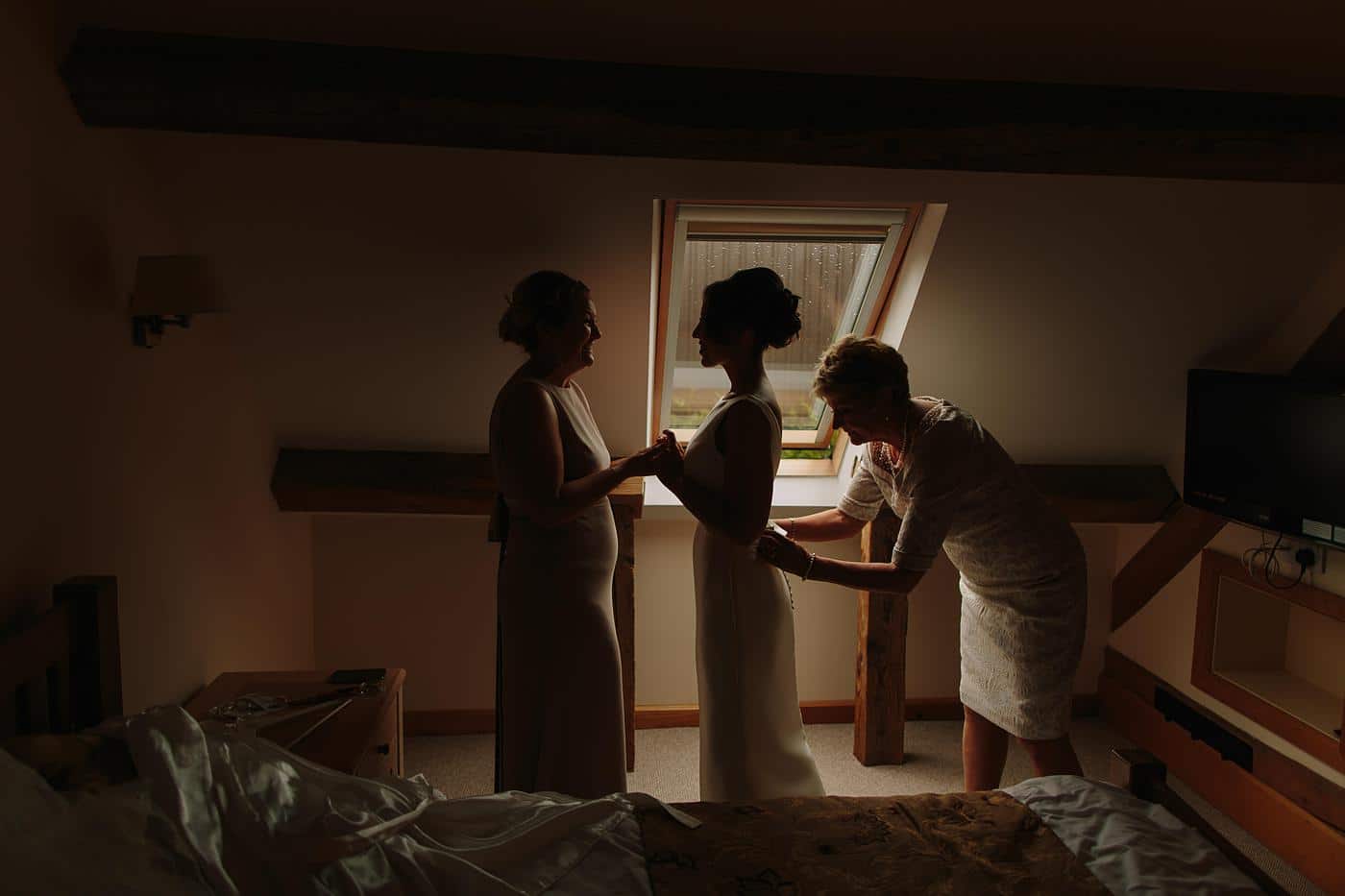final touches as the mother of the bride fastens up her dress
