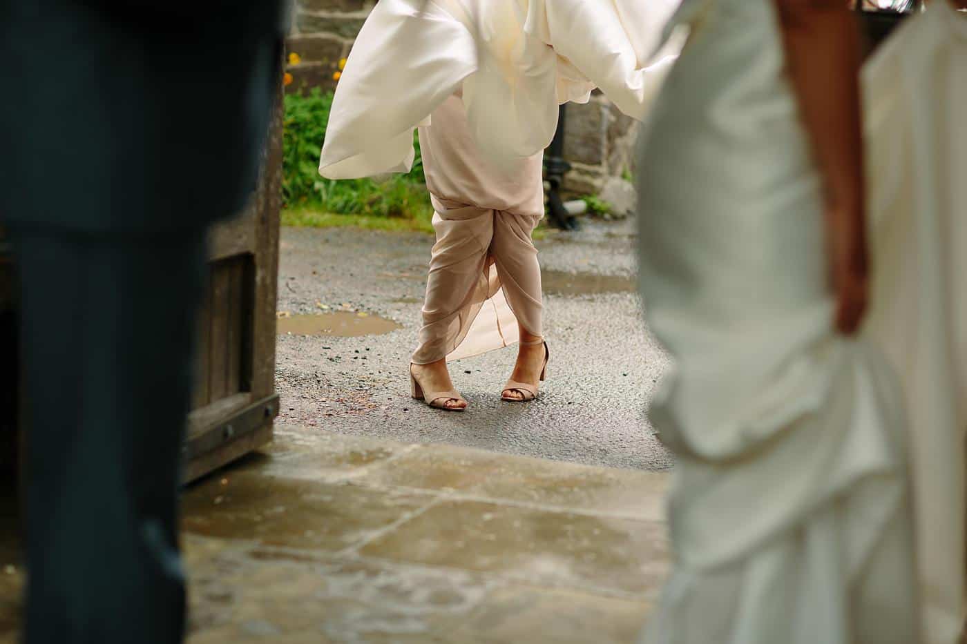 A woman in a stunning wedding dress is gracefully walking down the street near Wistanstow Village Hall, radiating sheer elegance on her special day.