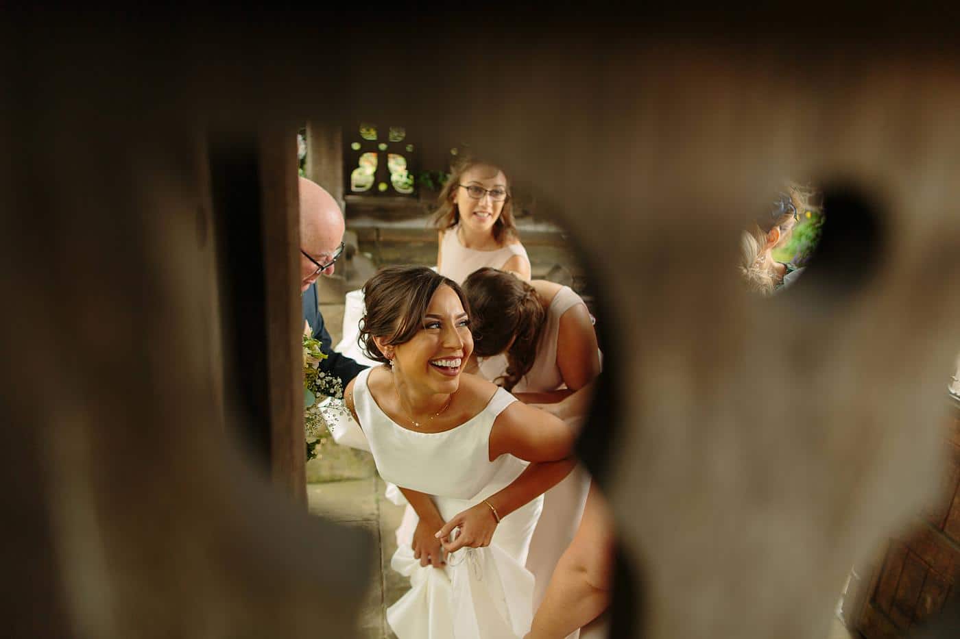 A bride and her bridesmaids at a Wistanstow Village Hall wedding, peeking through a wooden door.