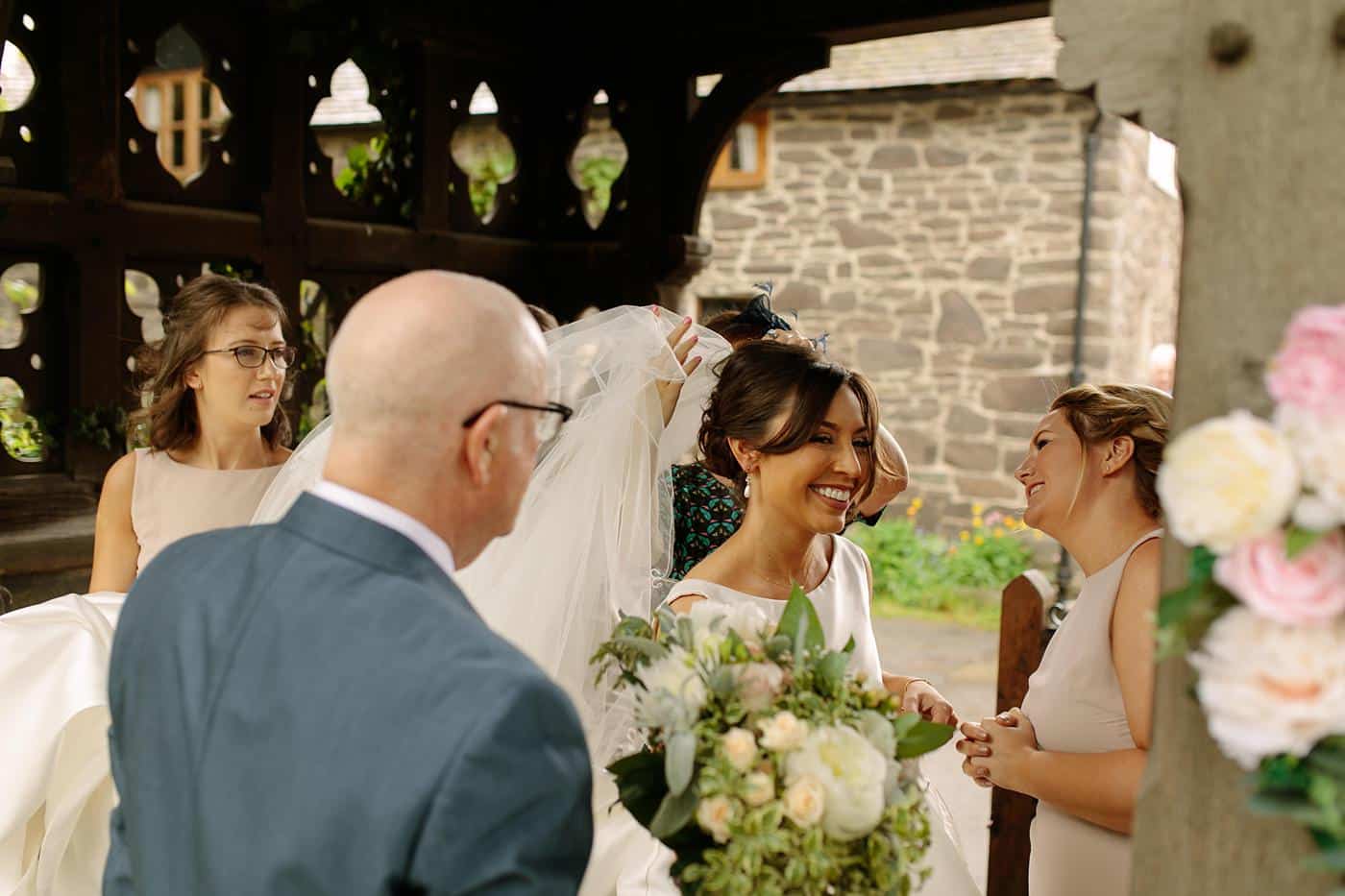 A bride walks down the aisle at her Wistanstow Village Hall wedding, accompanied by her bridesmaids.