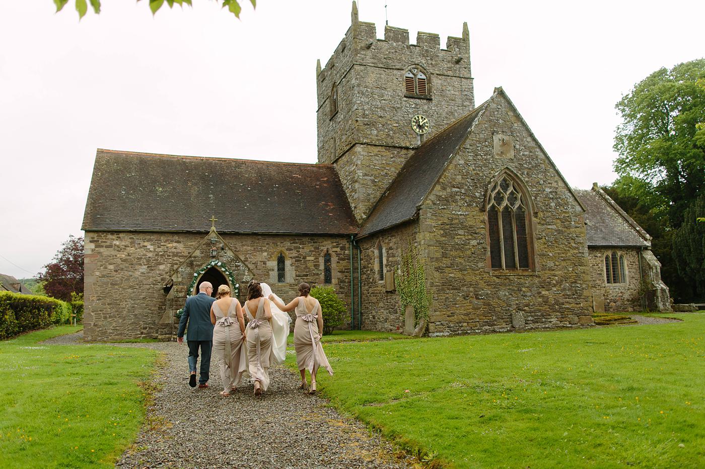 A group of people walking in front of Wistanstow Village Hall after a wedding ceremony at a nearby church.