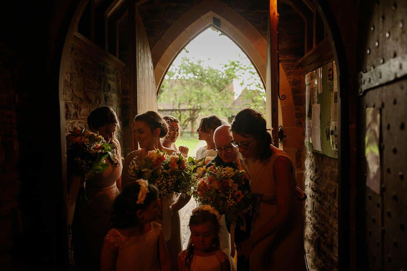 Bridesmaids at Wistanstow Village Hall Wedding standing in the doorway of a church.