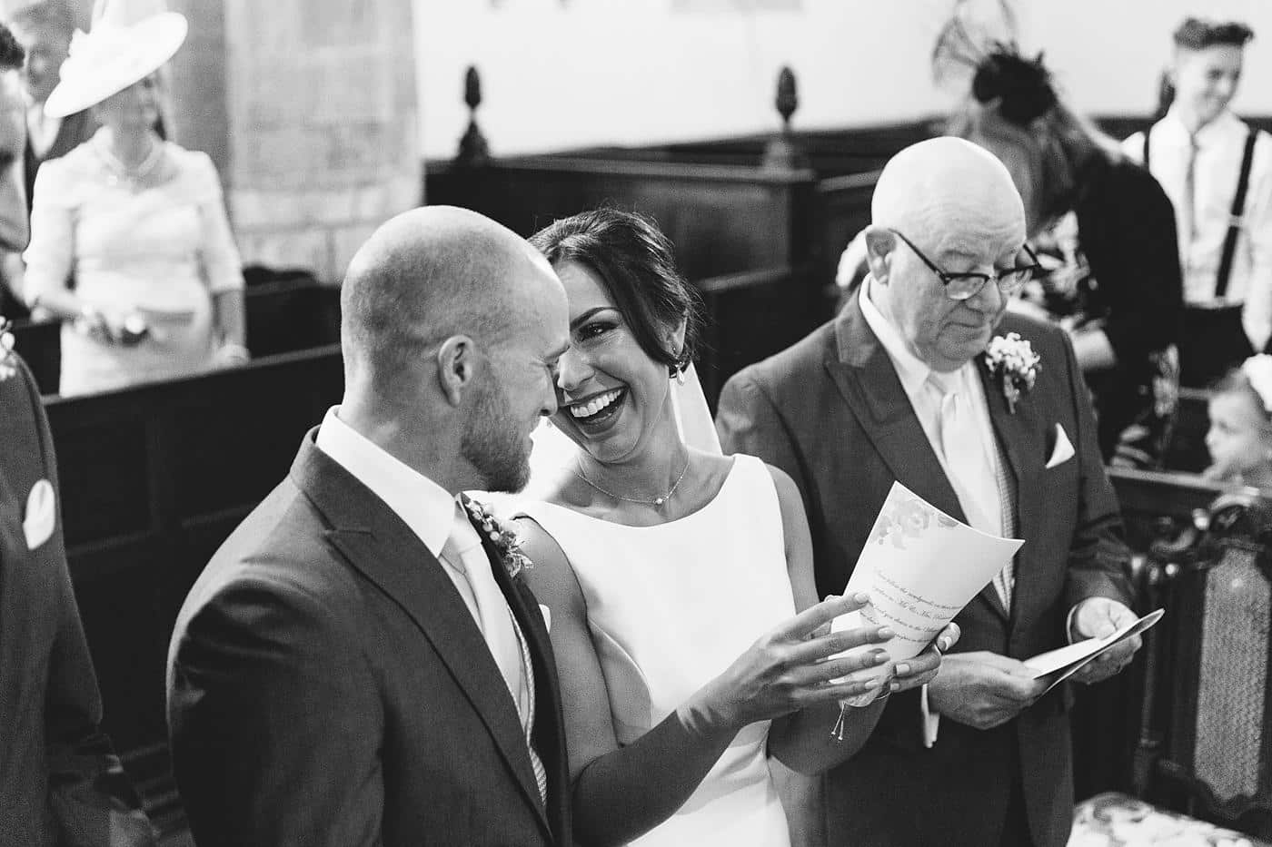 A joyful bride and groom in Wistanstow Village Hall Wedding, laughing during their ceremony.