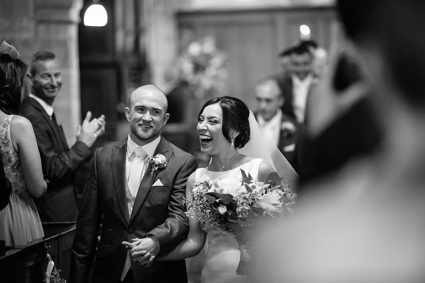 Black and white photo of Wistanstow Village Hall wedding, with the bride and groom walking down the aisle.