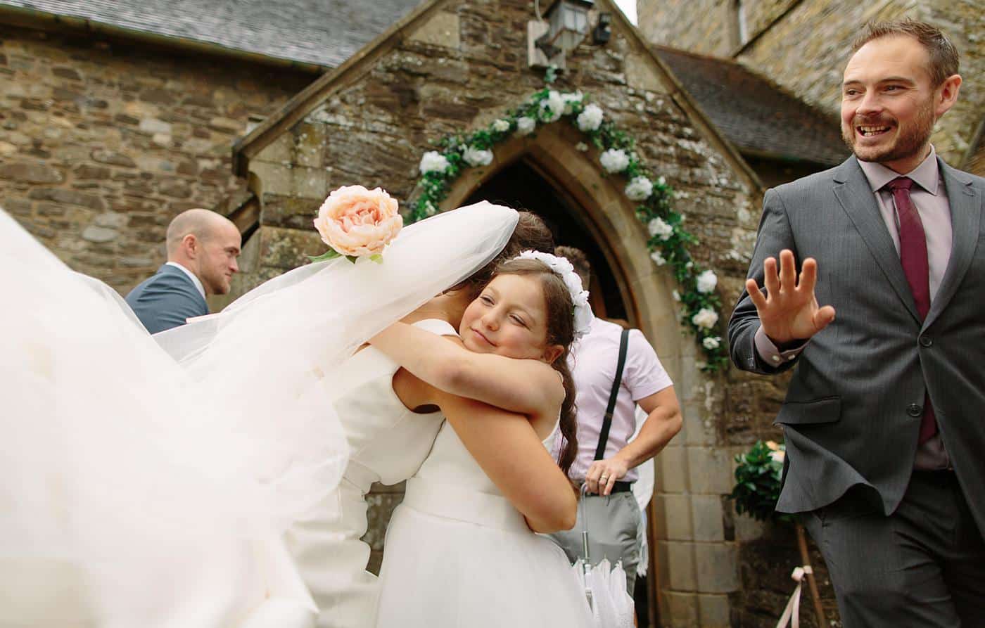 A bride and groom hugging outside Wistanstow Village Hall after their wedding ceremony at the neighboring church.