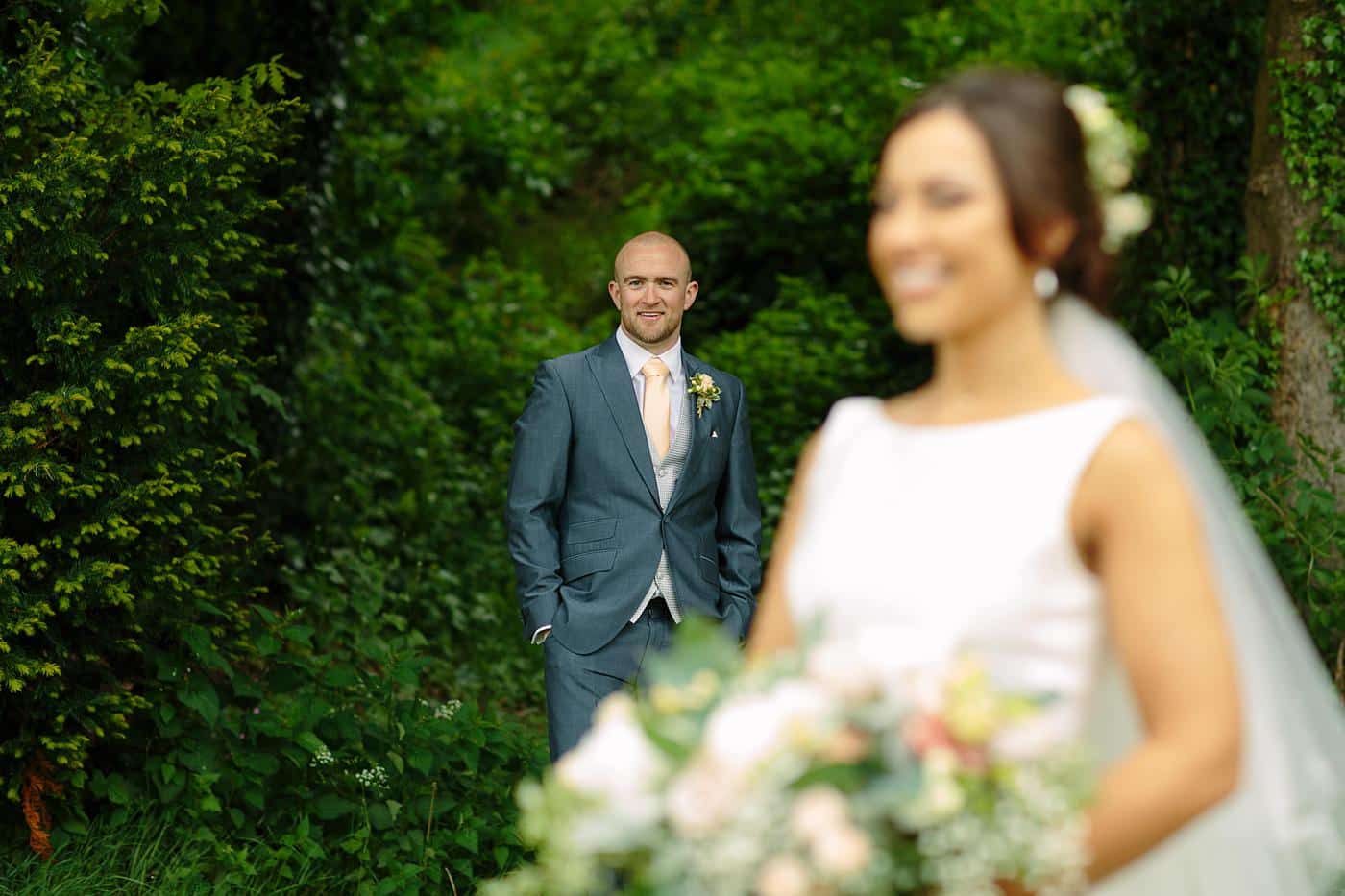 A bride and groom standing in the enchanting woods surrounding Wistanstow Village Hall on their wedding day.