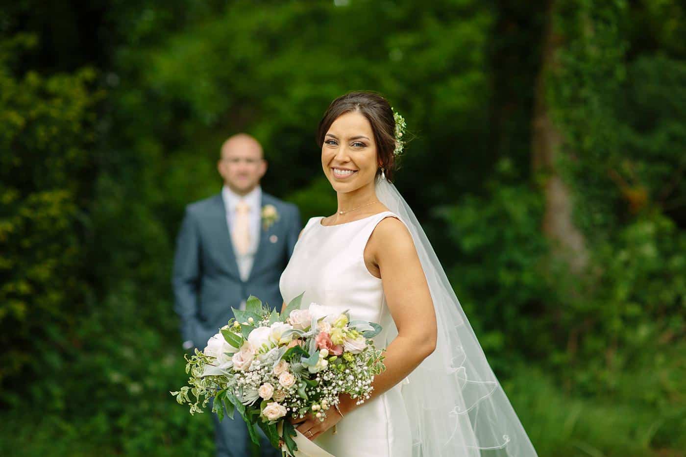 A bride and groom standing next to each other in the woods at their Wistanstow Village Hall wedding.