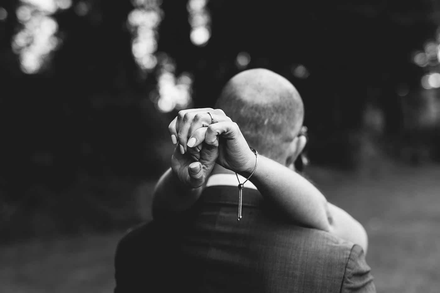 A black and white photo of a man holding a woman's hand at their Wistanstow Village Hall wedding.