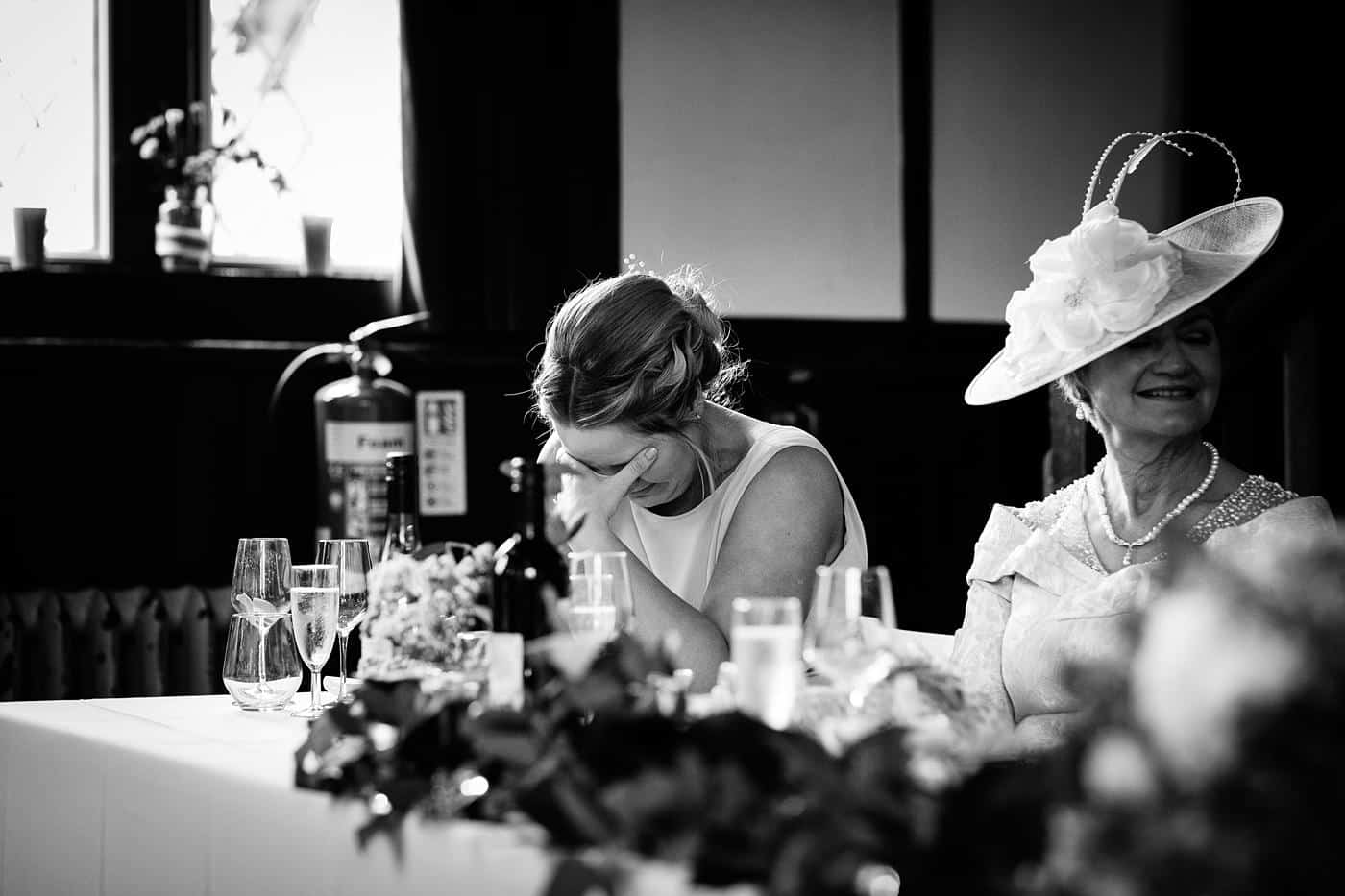 A black and white photo of a woman sitting at a table at Wistanstow Village Hall.