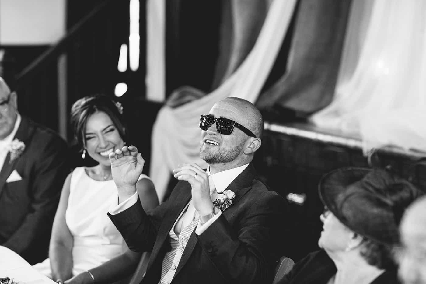 Black and white photo of a man drinking a glass of wine at a Wistanstow Village Hall wedding.