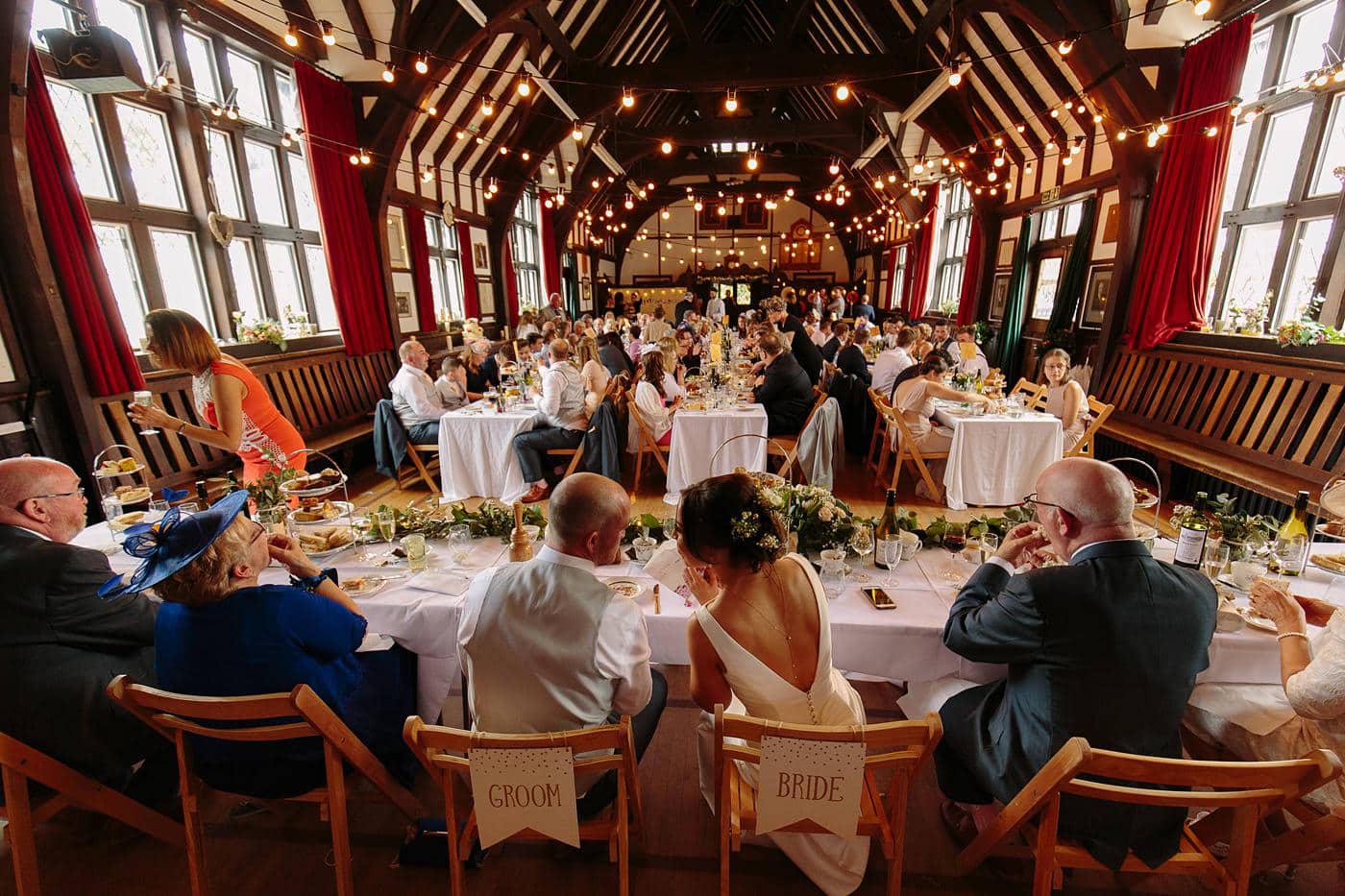 Wistanstow Village Hall Wedding - A group of people sitting at tables in a large room.