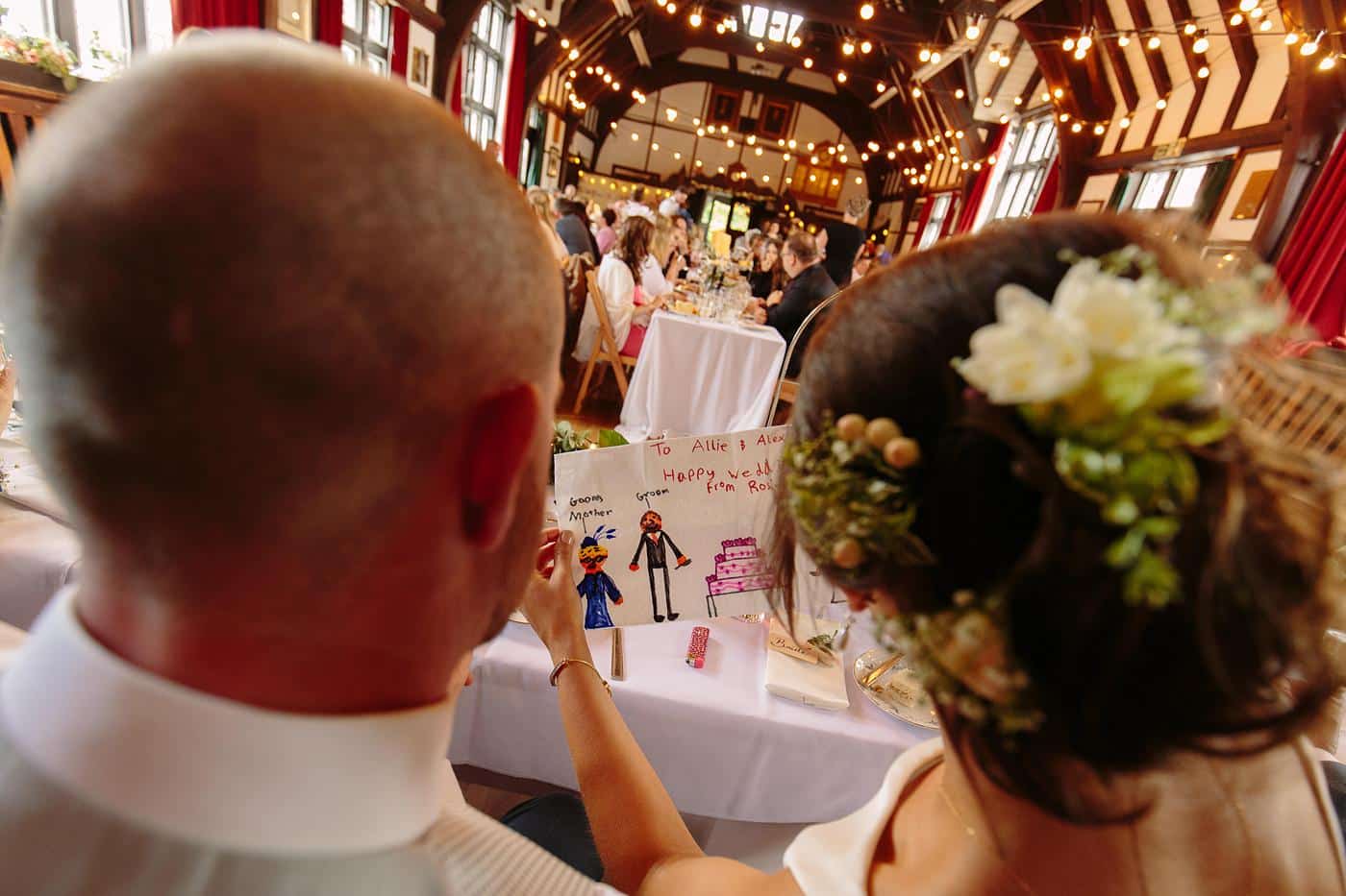 A beautiful wedding reception takes place at Wistanstow Village Hall, where a beaming bride and groom celebrate their special day surrounded by loved ones.