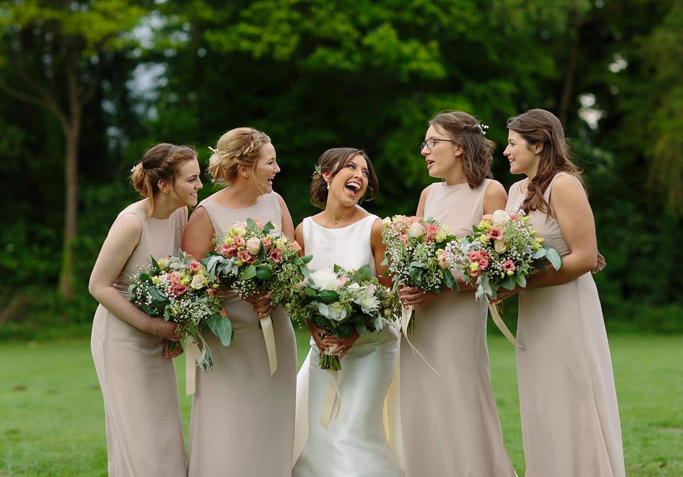 A bridal party laughing in a field at a Wistanstow Village Hall Wedding.