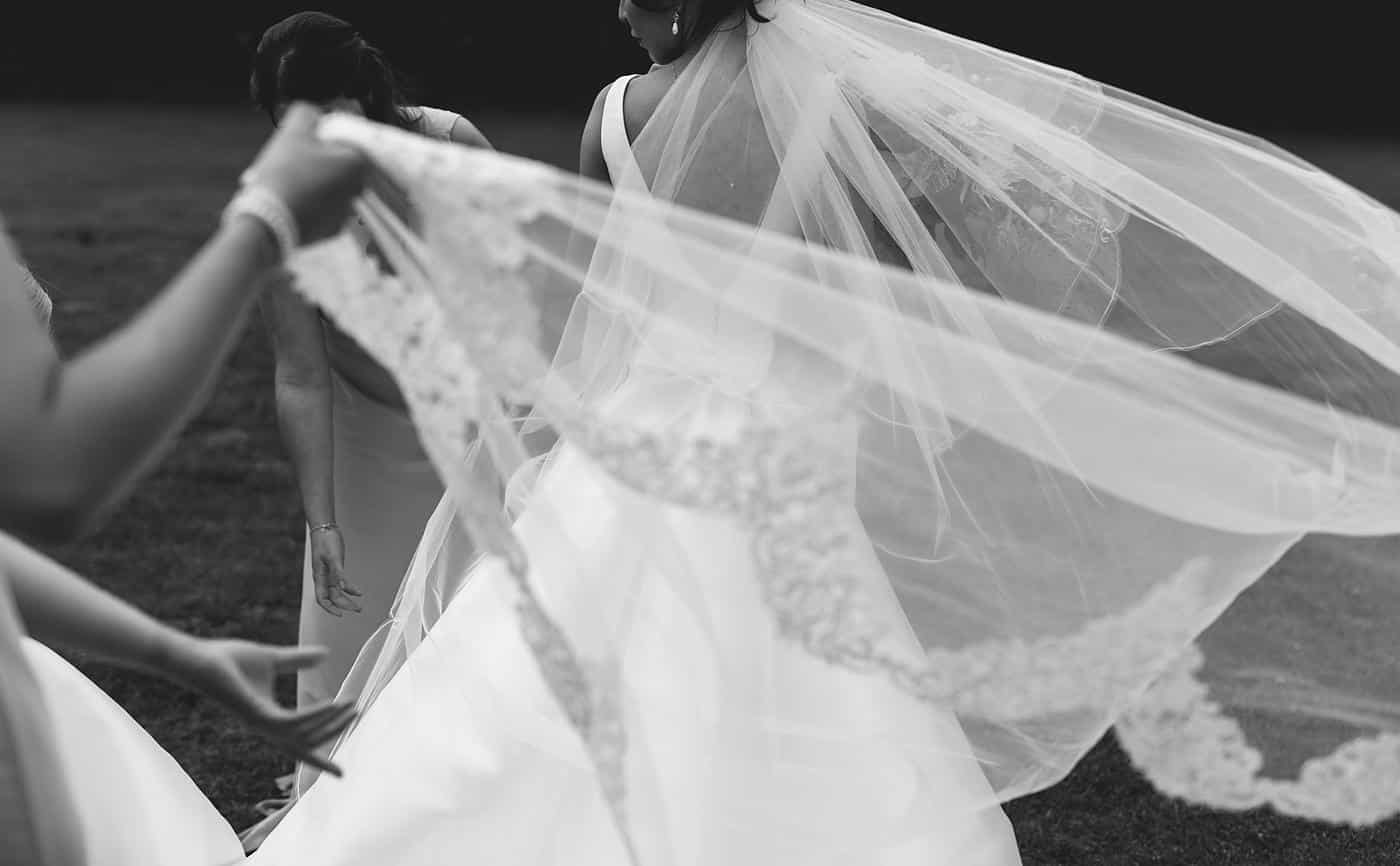 In the picturesque Wistanstow Village Hall Wedding, a radiant bride and her joyful bridesmaids gather beneath a beautifully adorned veil.