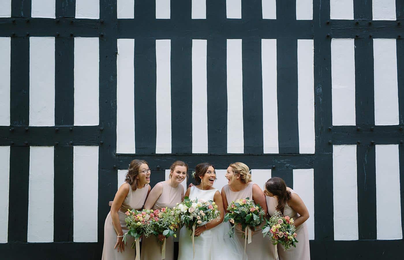 Bridesmaids at a Wistanstow Village Hall Wedding pose in front of a black and white wall.