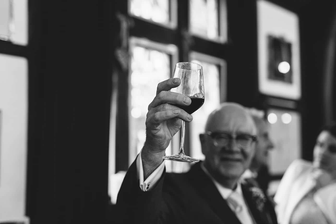 At the picturesque Wistanstow Village Hall Wedding, a dapper man gracefully holds a glass of wine, adding elegance to the celebration.
