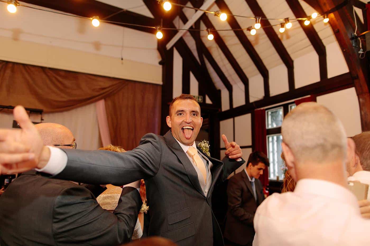 A man in a suit dancing at a Wistanstow Village Hall wedding reception.