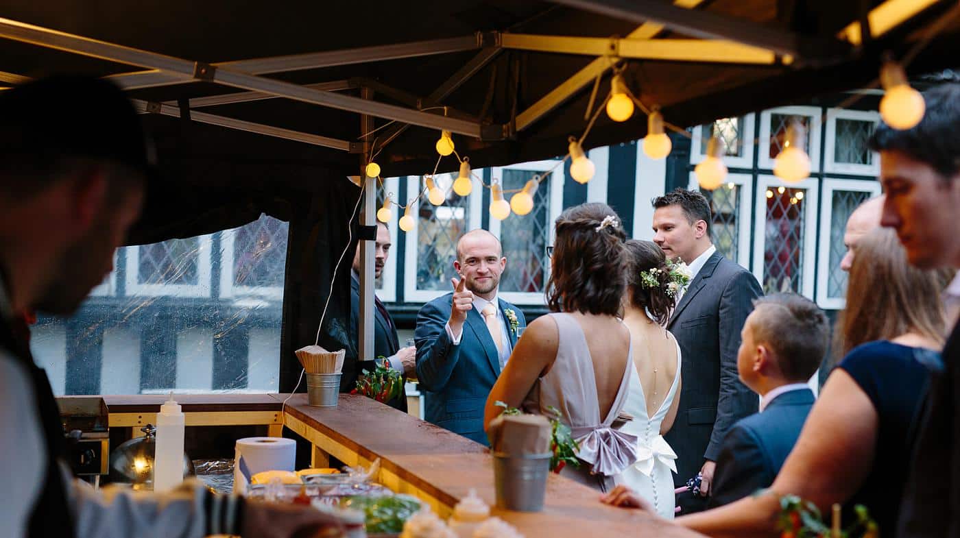A group of people standing around a bar at a Wistanstow Village Hall wedding.