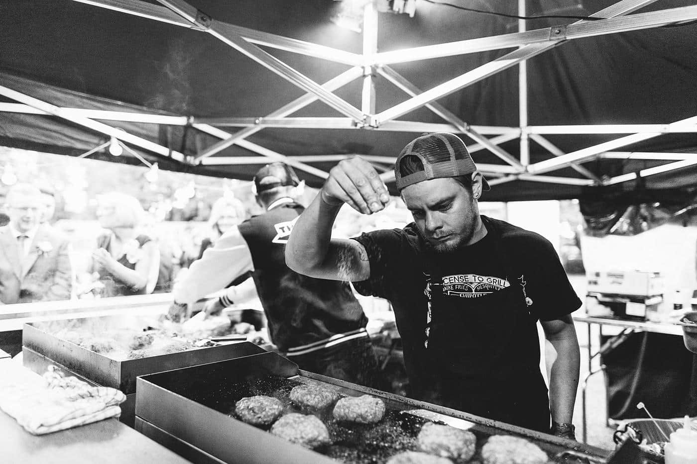 A man is preparing food on a grill at a Wistanstow Village Hall wedding.