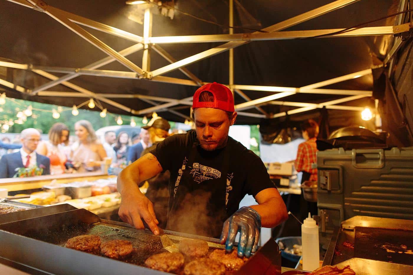 A man is preparing food on a grill at a Wistanstow Village Hall wedding.
