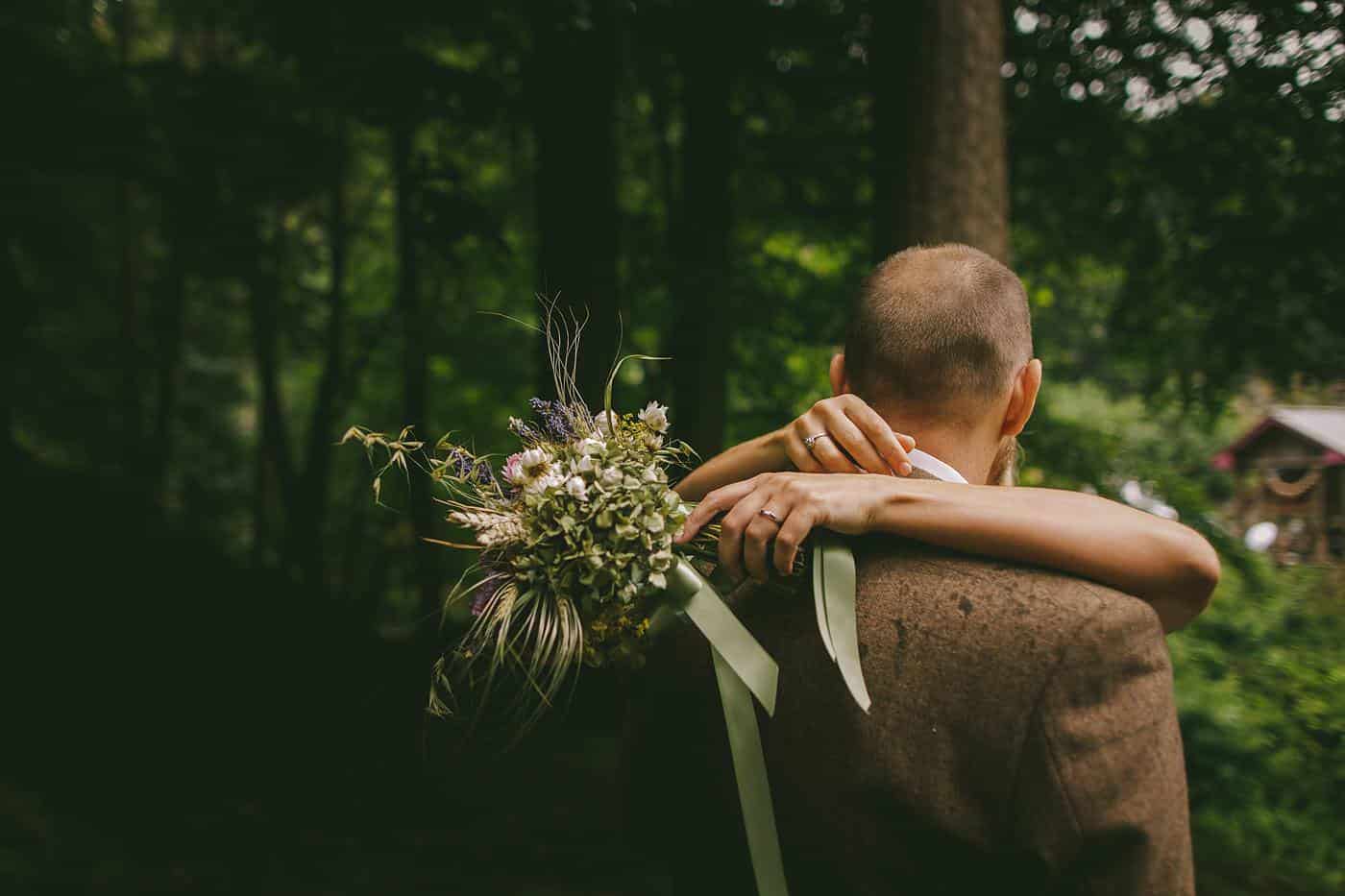 A bride and groom embracing in the enchanting woods on their Wedding Day.