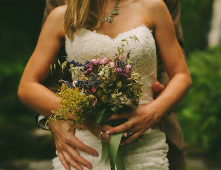 On their Wedding Day, a bride and groom lovingly hold a bouquet in the enchanting woods near Pistyll Rhaeadr.