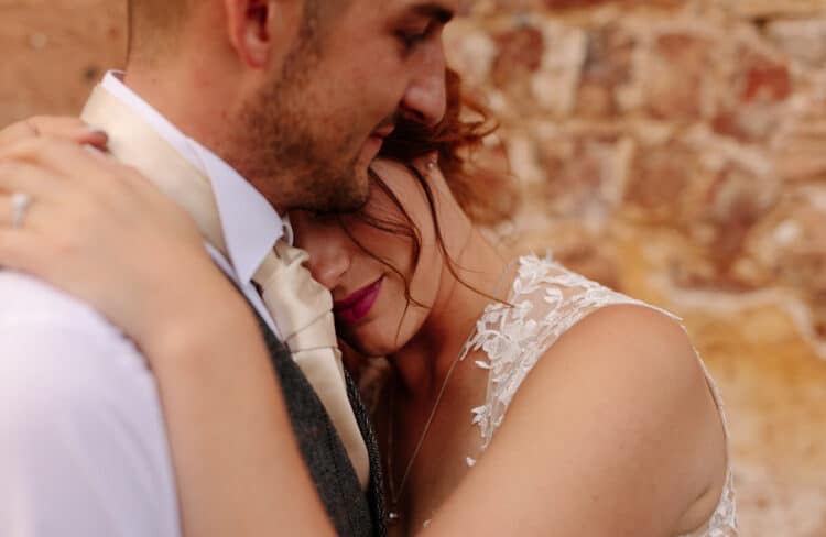 A bride and groom hugging in front of a stone wall for their Pentre Mawr Wedding Photography.