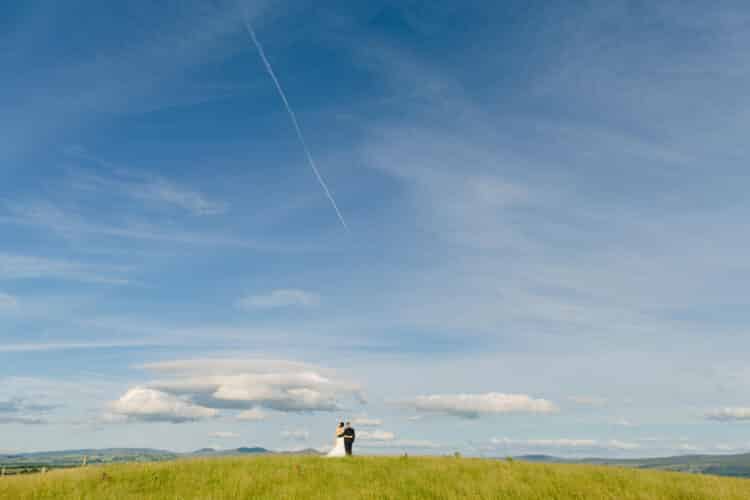 A North Wales Wedding with a bride and groom standing on top of a grassy hill.