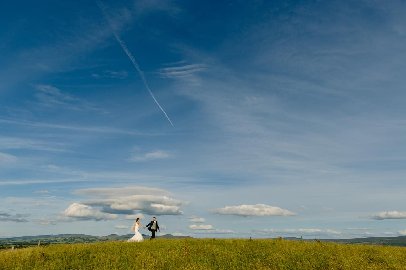 Bride and Groom walk across welsh hillside at a North Wales Wedding
