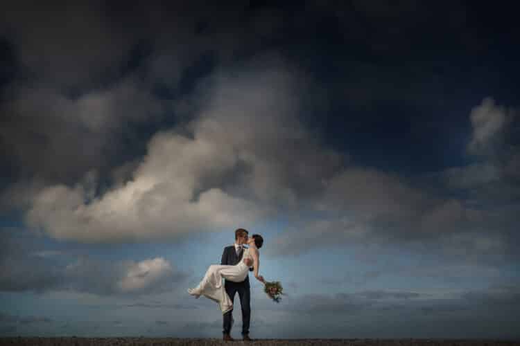 bride and groom embrace on Penmon Point after their Tros Yr Afon wedding ceremony
