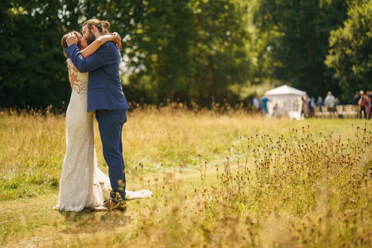 A bride and groom hugging in a picturesque field near Sychpwll Llandrinio.