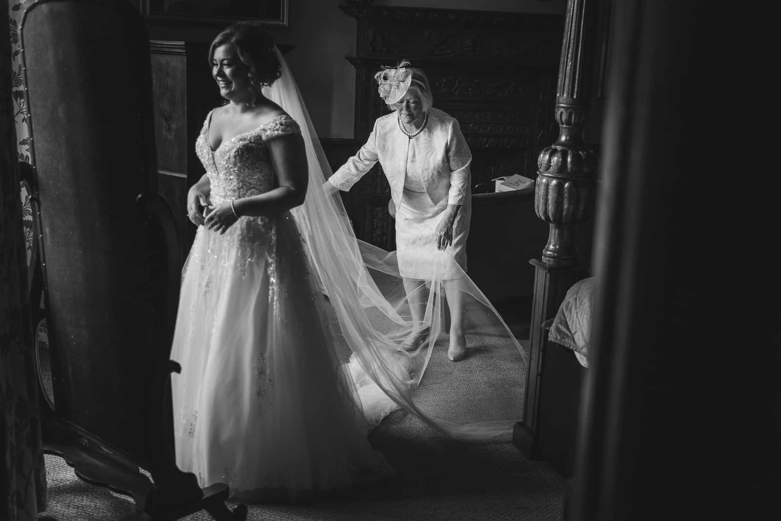 A black and white photo of a bride getting ready in a room at Rowton Castle in Shrewsbury.