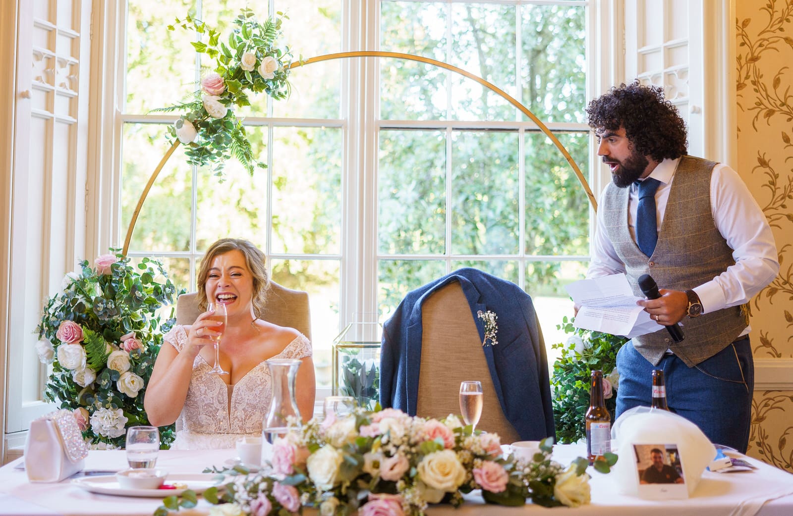 At Rowton Castle, a stunning wedding venue, a radiant bride and dashing groom share heartfelt laughter during their wedding speech.