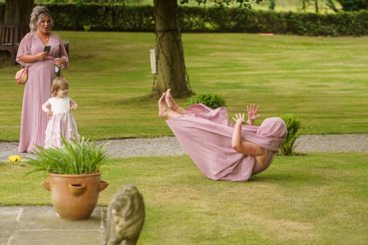 A Shropshire wedding photographer captures a woman in a pink dress falling down in a garden.