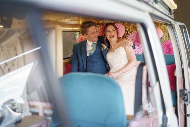 A bride and groom drive off in a pink VW camper van after their Shropshire wedding at Pimhill Barn.