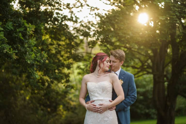 A bride and groom embracing under a tree at their Shropshire wedding ceremony at Pimhill Barn.