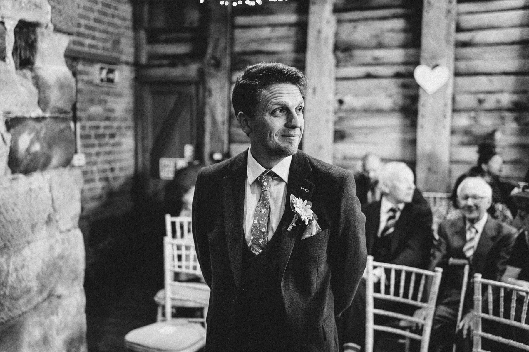 A black and white photo of a groom walking down the aisle at a Shropshire wedding.