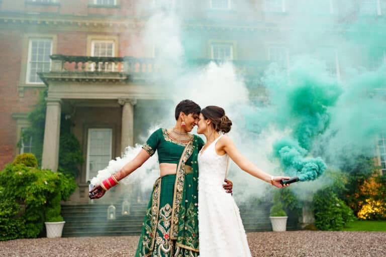 A bride and groom pose with smoke bombs in front of a Davenport House mansion for their wedding photography.