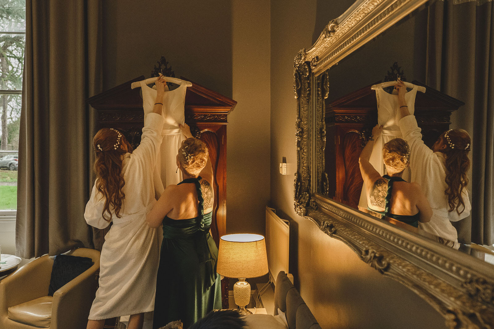 a bride getting ready in a room with a mirror.