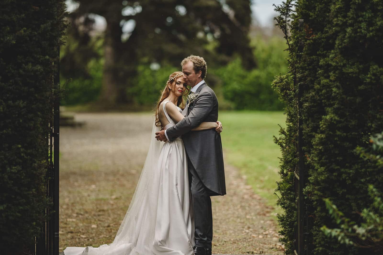 a bride and groom embracing in a garden.
