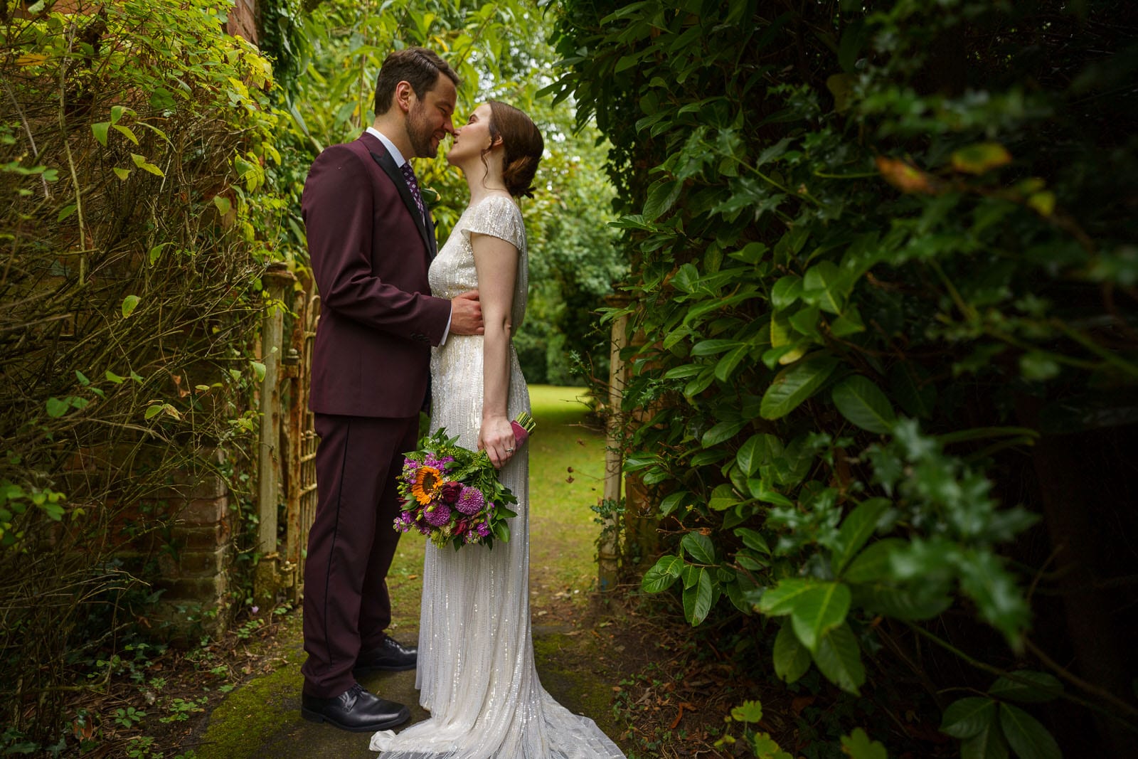 a bride and groom kissing in a garden.