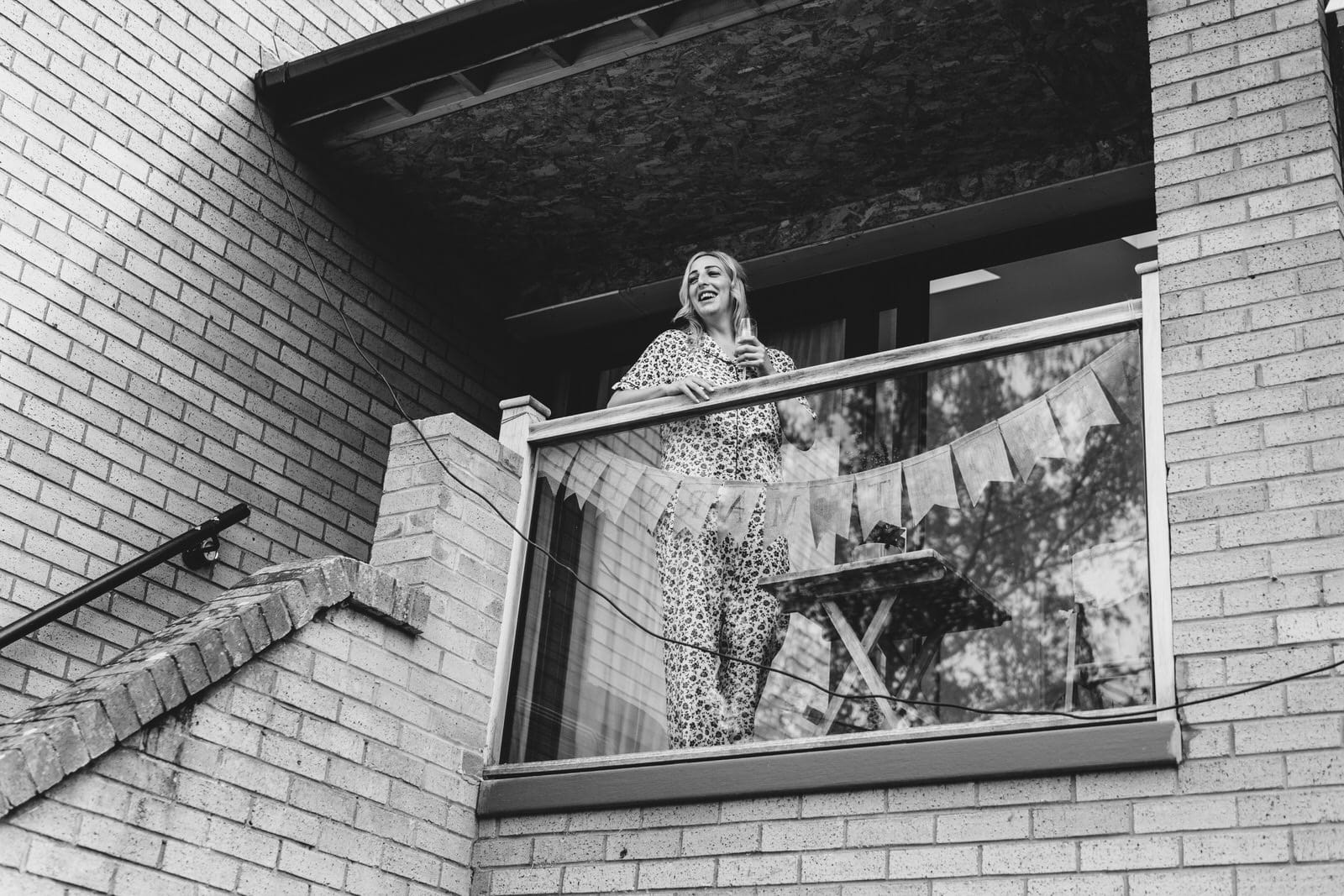 a black and white photo of a woman standing on a balcony.